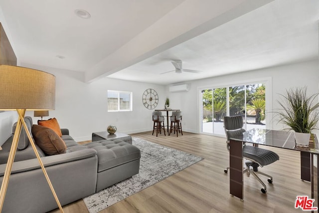 living room featuring ceiling fan, beam ceiling, a wall unit AC, and light hardwood / wood-style flooring