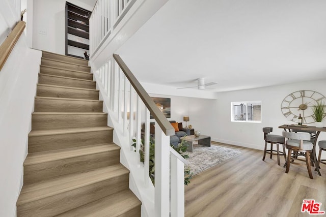 stairway with hardwood / wood-style floors and ceiling fan