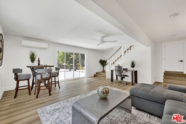 living room with a wall unit AC, ceiling fan, and light hardwood / wood-style flooring