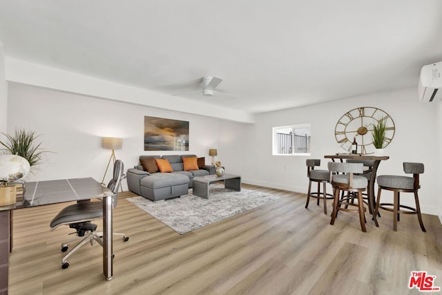 living room with a wall mounted AC, ceiling fan, and light hardwood / wood-style floors