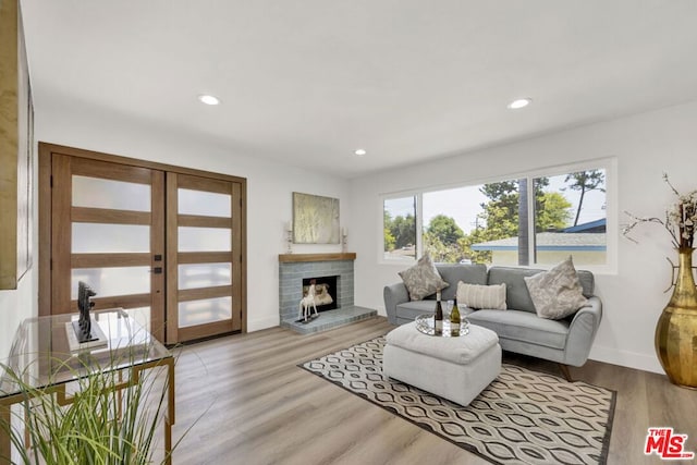 living room with light hardwood / wood-style flooring, french doors, and a brick fireplace