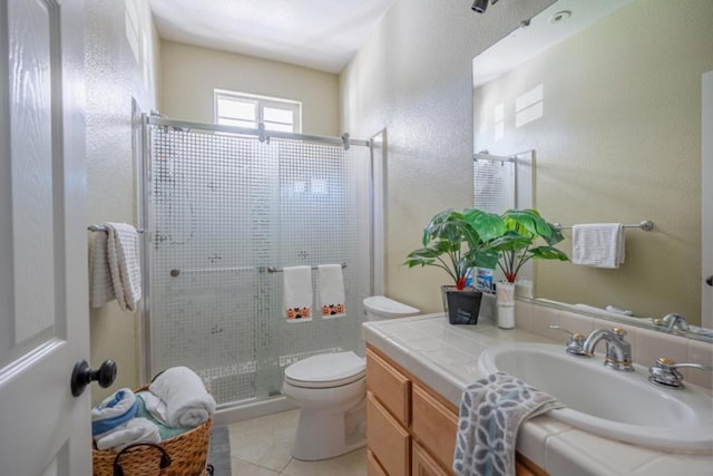 bathroom featuring tile patterned floors, vanity, toilet, and a shower with door