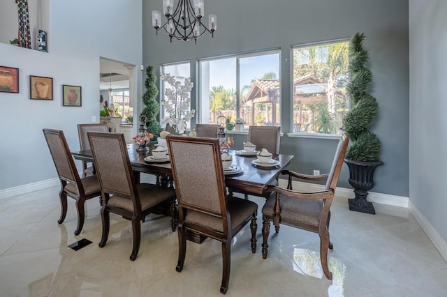 dining room featuring an inviting chandelier, light tile patterned floors, and a towering ceiling