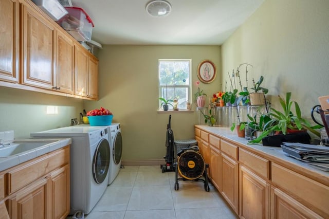 laundry area with light tile patterned floors, sink, washing machine and dryer, and cabinets