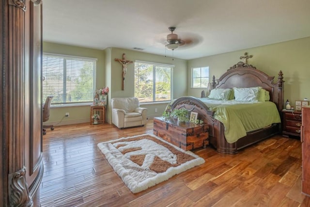 bedroom with multiple windows, hardwood / wood-style flooring, and ceiling fan