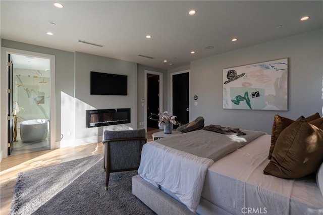 bedroom with a glass covered fireplace, visible vents, and recessed lighting