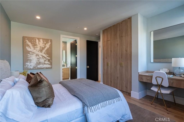 bedroom with a closet, baseboards, recessed lighting, ensuite bath, and wood finished floors