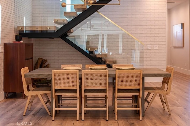 dining area with wood-type flooring and brick wall