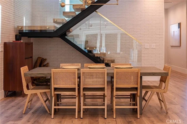 dining room with brick wall, wood finished floors, and baseboards
