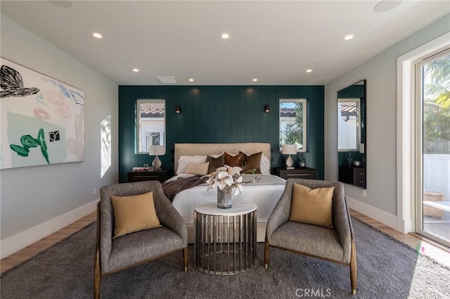 bedroom featuring hardwood / wood-style flooring, wood walls, access to outside, and multiple windows