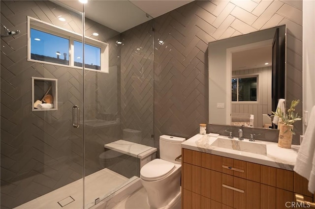 bathroom with vanity, toilet, tile walls, and a shower with shower door