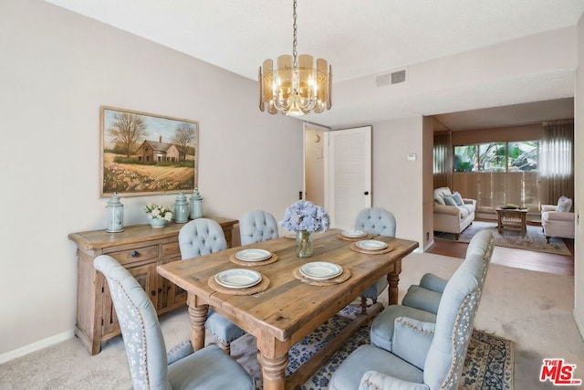 carpeted dining room featuring a notable chandelier