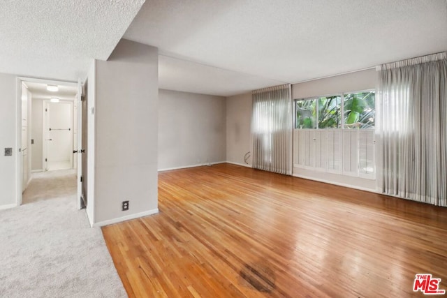 empty room featuring wood-type flooring and a textured ceiling