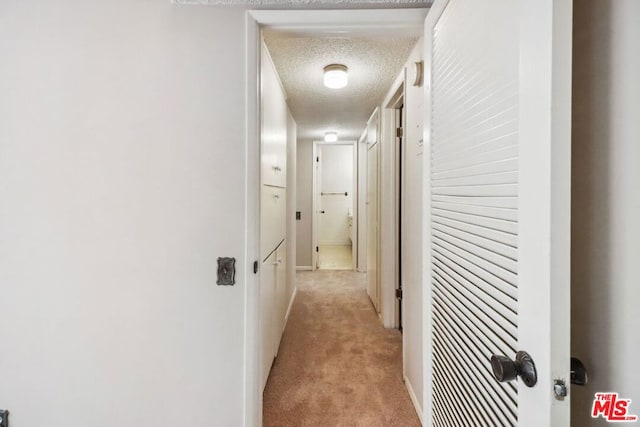 hallway featuring light carpet and a textured ceiling