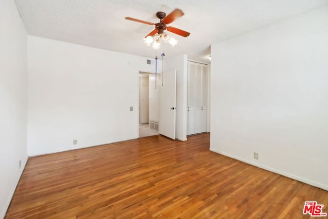 unfurnished room with hardwood / wood-style flooring and a textured ceiling