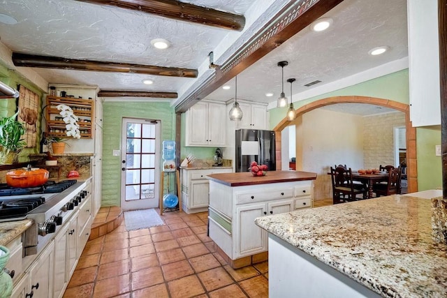 kitchen featuring white cabinetry, beamed ceiling, a textured ceiling, decorative light fixtures, and fridge