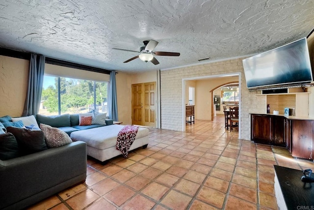 tiled living room with ceiling fan, plenty of natural light, and a textured ceiling