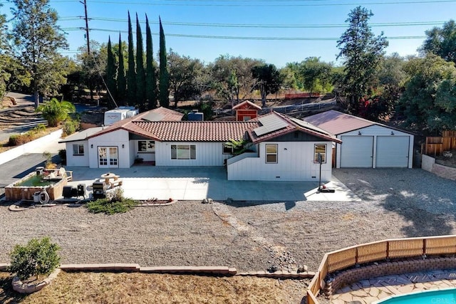 view of front of property featuring a garage, an outbuilding, a patio, and french doors