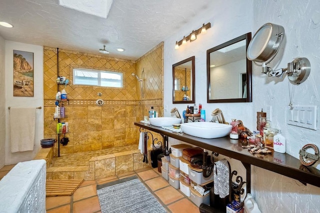 bathroom with tile patterned flooring, a tile shower, vanity, and a textured ceiling