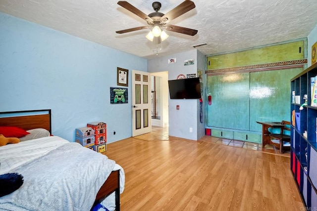 bedroom featuring ceiling fan, a closet, a textured ceiling, and light hardwood / wood-style flooring