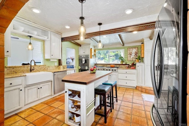 kitchen featuring white cabinets, beam ceiling, sink, and appliances with stainless steel finishes