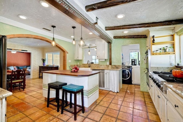 kitchen with beamed ceiling, white cabinets, a textured ceiling, and appliances with stainless steel finishes