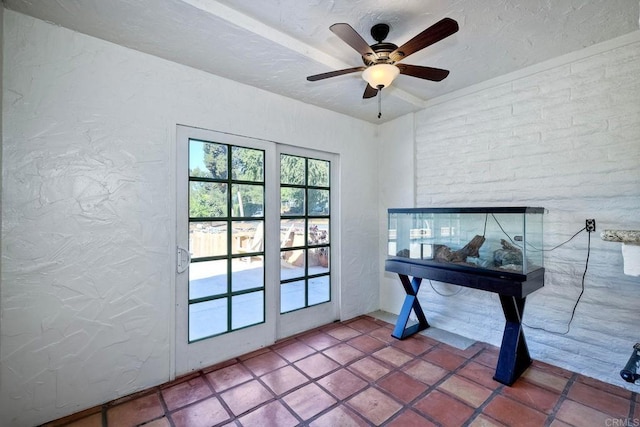 doorway featuring ceiling fan and a textured ceiling