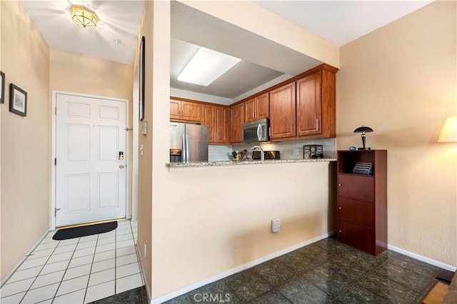 kitchen with kitchen peninsula, light stone counters, sink, and appliances with stainless steel finishes