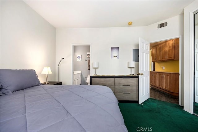 bedroom featuring ensuite bath and dark carpet