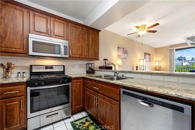 kitchen with backsplash, sink, light tile patterned floors, light stone counters, and stainless steel appliances