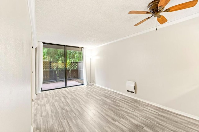 empty room with ornamental molding, ceiling fan, light hardwood / wood-style floors, floor to ceiling windows, and a textured ceiling