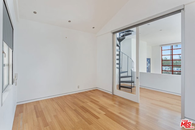 unfurnished room featuring hardwood / wood-style flooring and lofted ceiling