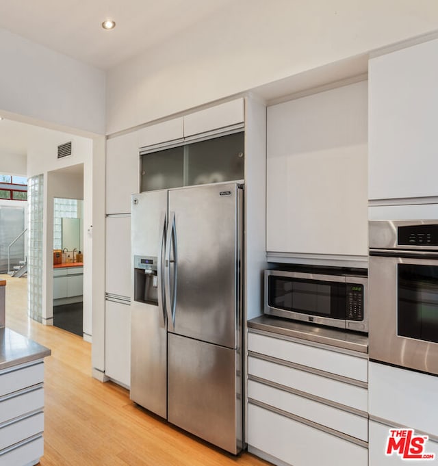 kitchen featuring appliances with stainless steel finishes, white cabinets, and light hardwood / wood-style floors