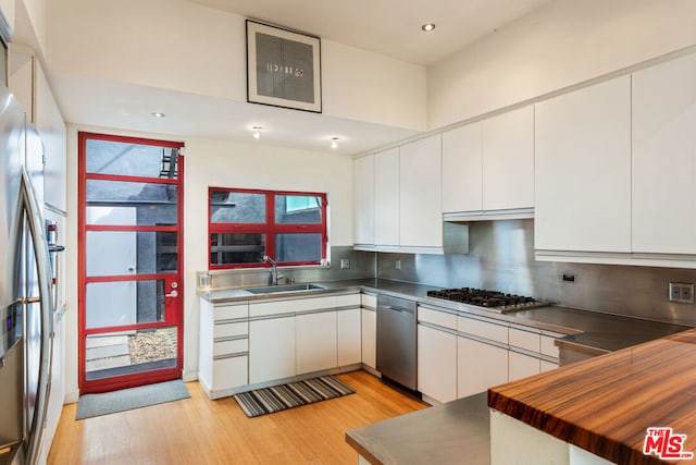 kitchen with white cabinetry, appliances with stainless steel finishes, sink, and light hardwood / wood-style floors