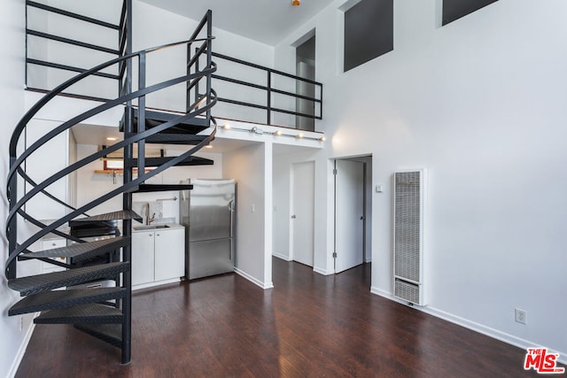 stairway with hardwood / wood-style floors and a high ceiling