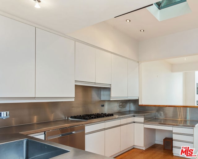 kitchen with white cabinetry, decorative backsplash, appliances with stainless steel finishes, and stainless steel counters