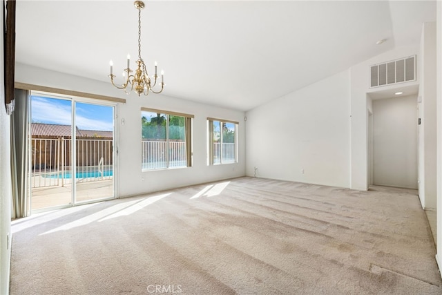 carpeted empty room with lofted ceiling and a chandelier