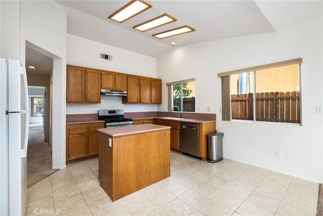 kitchen featuring light tile patterned floors, stainless steel appliances, a kitchen island, and sink