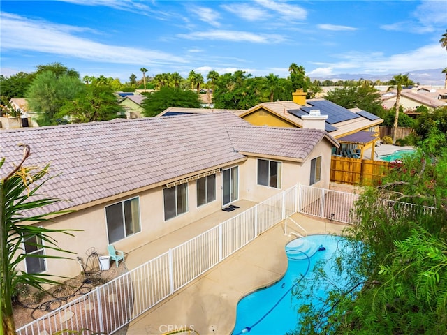 rear view of house with a fenced in pool