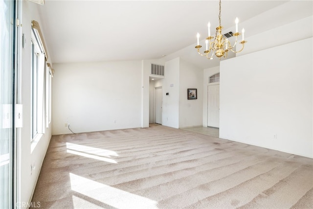 carpeted empty room featuring a chandelier and lofted ceiling