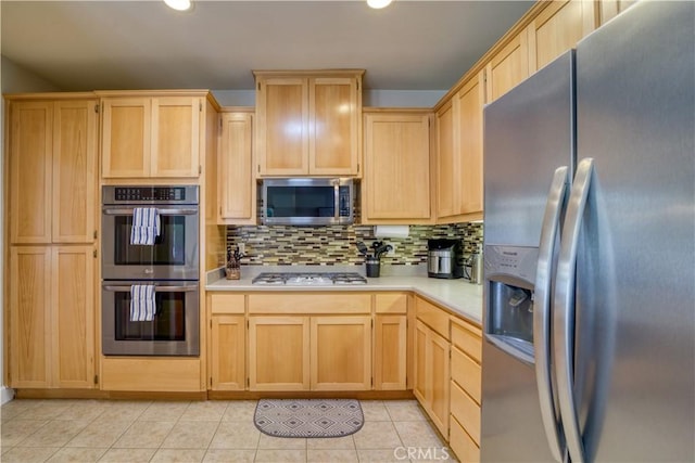 kitchen featuring light tile patterned flooring, stainless steel appliances, light brown cabinetry, and tasteful backsplash