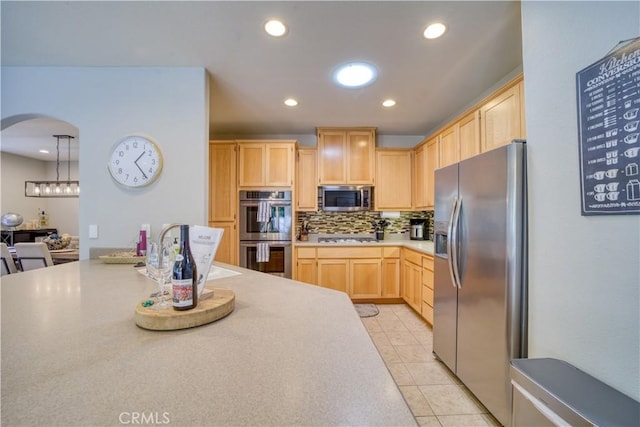 kitchen with light brown cabinets, backsplash, decorative light fixtures, light tile patterned flooring, and stainless steel appliances