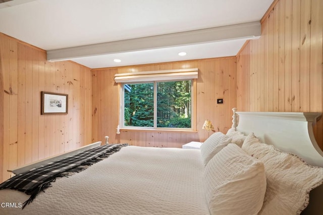 bedroom featuring beam ceiling and wood walls