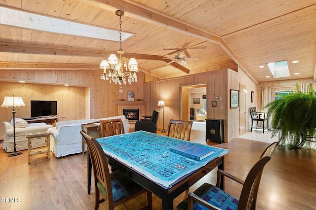 dining space with wood ceiling, vaulted ceiling with skylight, wood-type flooring, and ceiling fan with notable chandelier