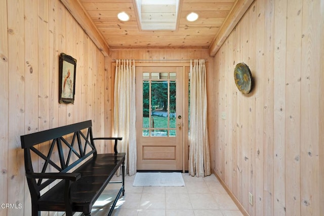 doorway featuring a skylight, wood walls, light tile patterned flooring, and wooden ceiling