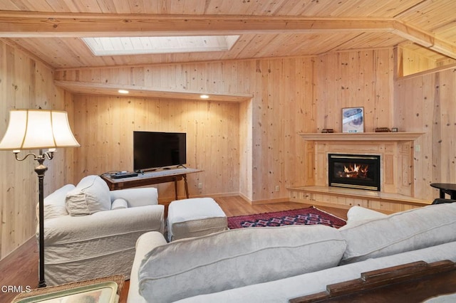 living room with vaulted ceiling with skylight, wood walls, and wood-type flooring