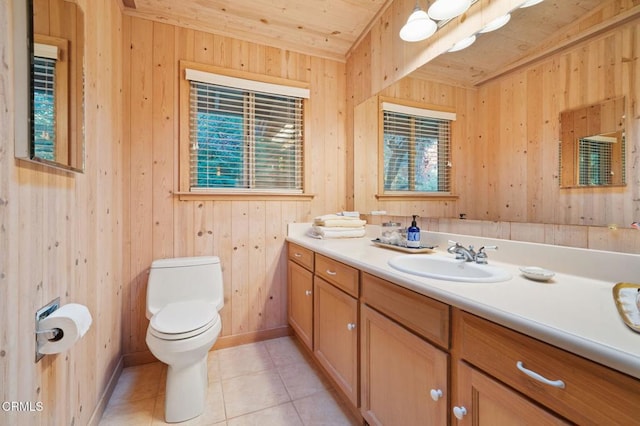 half bathroom featuring wood walls, vanity, toilet, and tile patterned floors