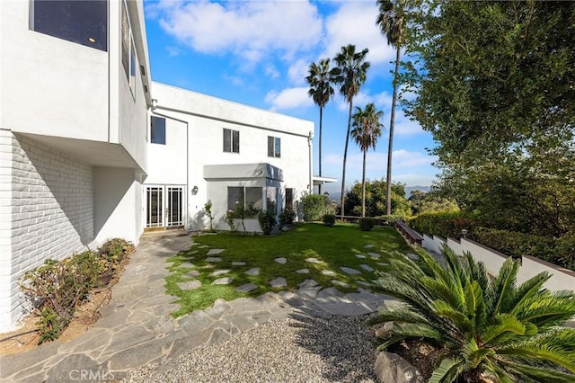 rear view of property with french doors and a lawn