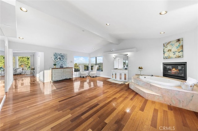 bathroom featuring vanity, vaulted ceiling with beams, hardwood / wood-style flooring, and tiled tub