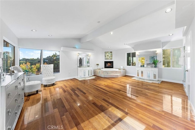 unfurnished living room with lofted ceiling with beams, a healthy amount of sunlight, and hardwood / wood-style flooring